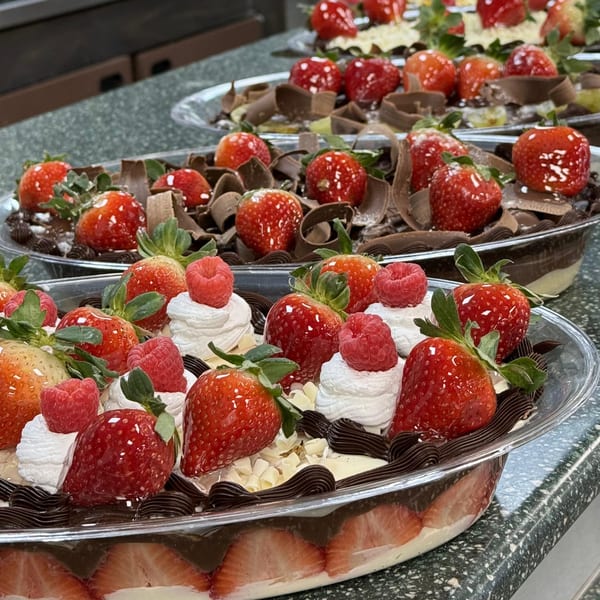 Brazilian desserts with strawberries, raspberries, chocolate shavings, and whipped cream in clear containers.