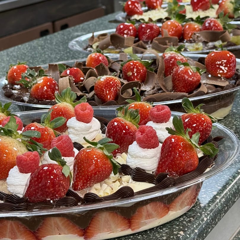 Brazilian desserts with strawberries, raspberries, chocolate shavings, and whipped cream in clear containers.