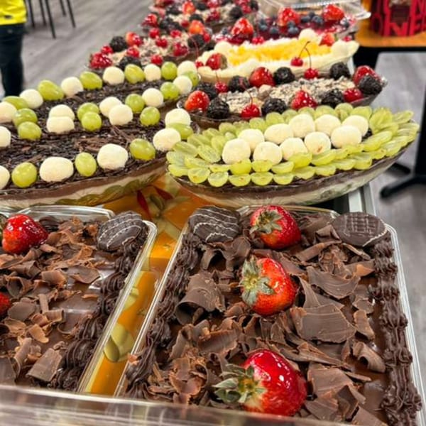 A display of Brazilian desserts, including chocolate cakes with strawberries and fruit-topped chocolate Easter eggs.