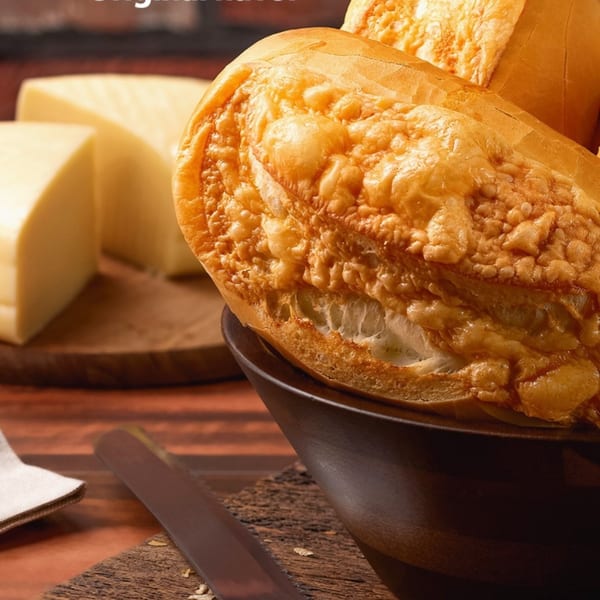 Golden-brown Brazilian cheese bread (pão de queijo) in a bowl, with cheese wedges in the background.