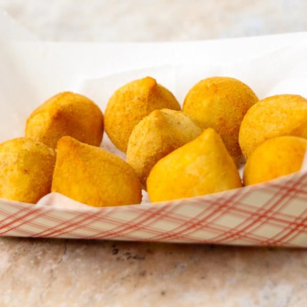 A paper tray filled with golden-brown Brazilian coxinha, a popular street food.