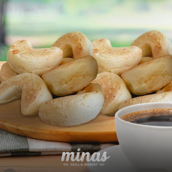 Brazilian cheese bread (pão de queijo) on a wooden board with a cup of coffee.